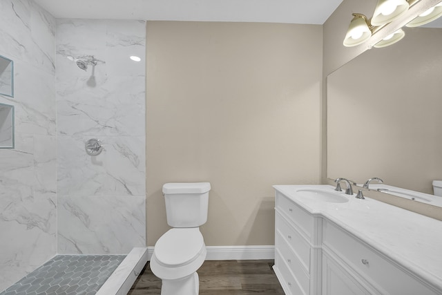 bathroom with vanity, toilet, wood-type flooring, and tiled shower