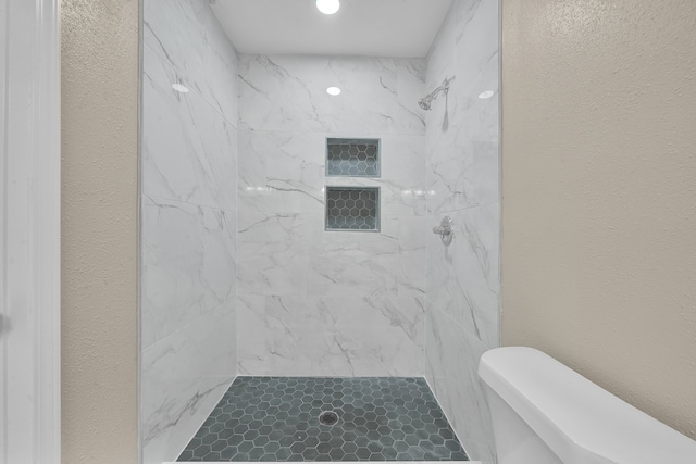 bathroom featuring toilet and a tile shower