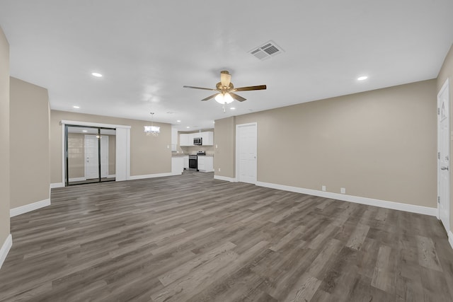 unfurnished living room with ceiling fan with notable chandelier and wood-type flooring