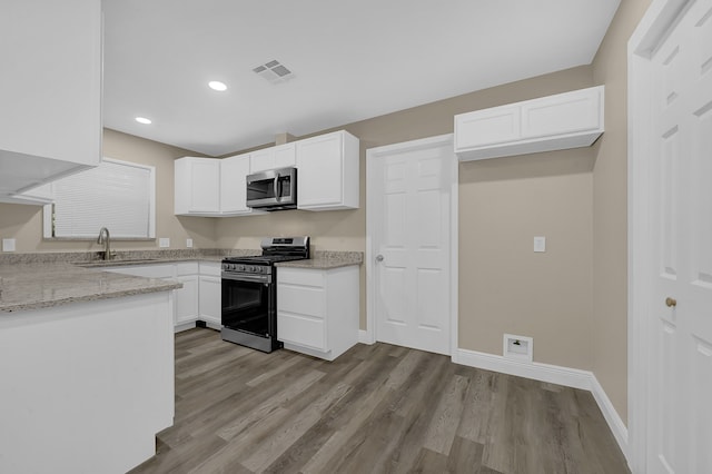 kitchen featuring sink, light wood-type flooring, light stone counters, white cabinetry, and stainless steel appliances