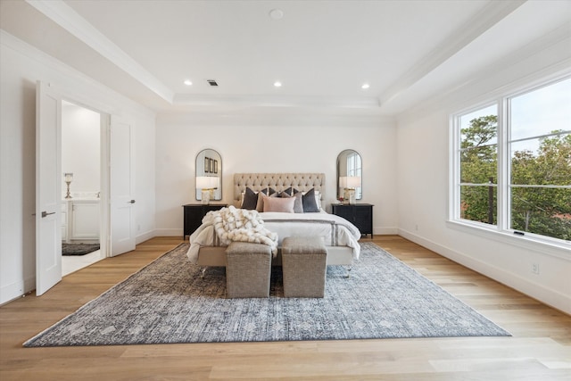 bedroom featuring ornamental molding, light hardwood / wood-style floors, and a tray ceiling