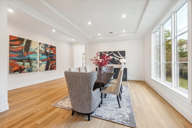 dining space featuring light wood-type flooring and a raised ceiling