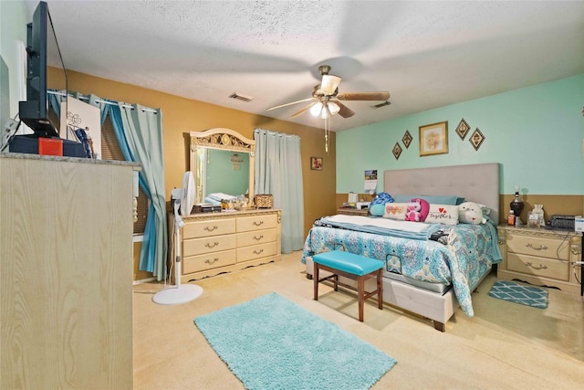 bedroom featuring ceiling fan, light colored carpet, and a textured ceiling