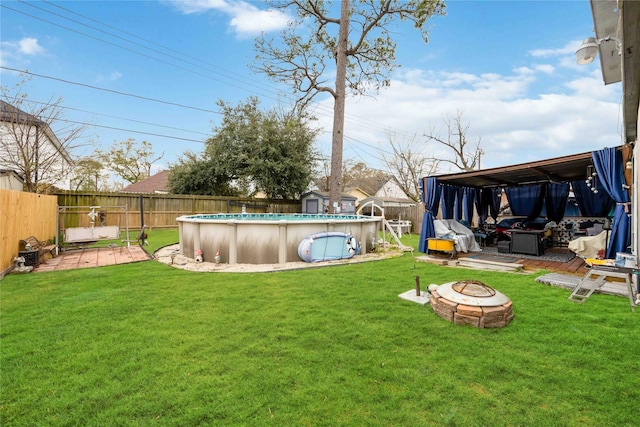 view of yard with an outdoor fire pit, a storage shed, and a fenced in pool