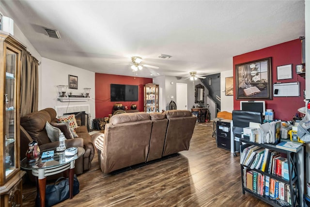 living room featuring ceiling fan, dark hardwood / wood-style floors, and a tile fireplace