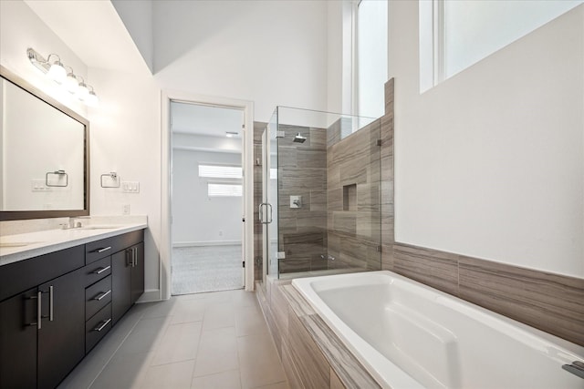 full bath with a garden tub, double vanity, a stall shower, a sink, and baseboards