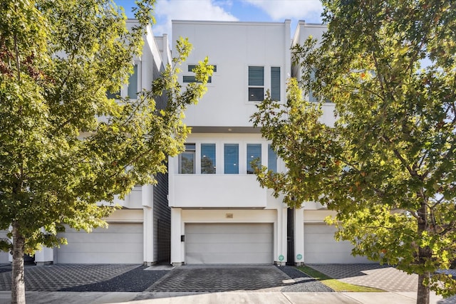 view of front of property featuring a garage, decorative driveway, and stucco siding