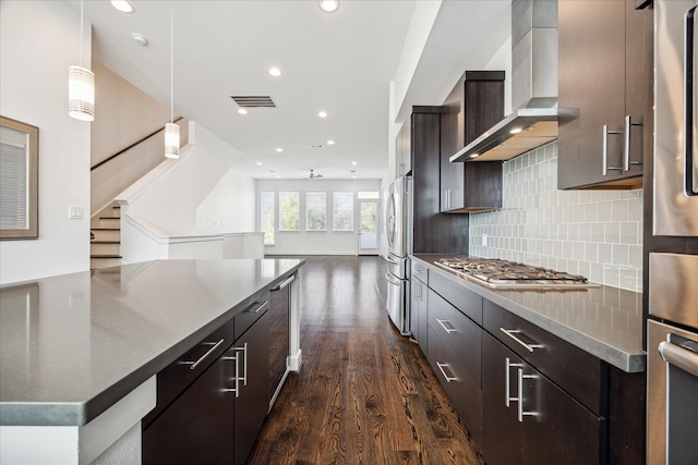 kitchen with dark wood-style floors, visible vents, decorative backsplash, appliances with stainless steel finishes, and wall chimney exhaust hood