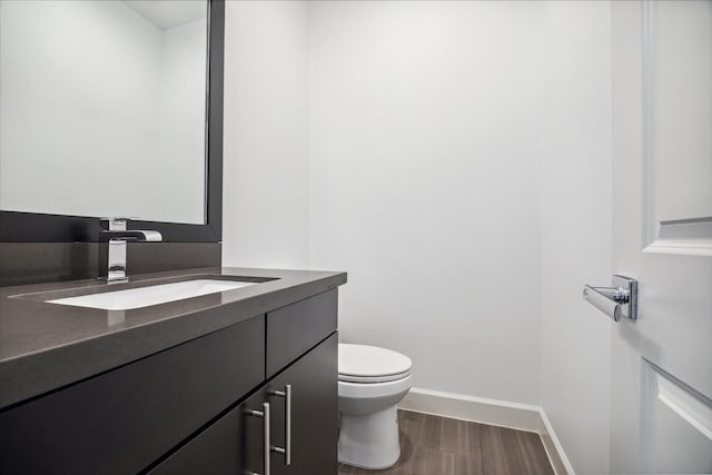 bathroom with baseboards, vanity, toilet, and wood finished floors