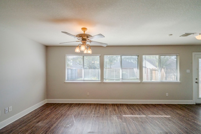 spare room with a textured ceiling, dark hardwood / wood-style floors, and a wealth of natural light