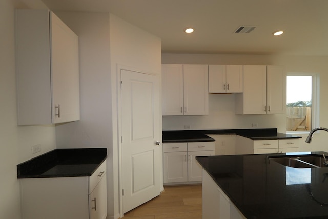 kitchen with white cabinets, light hardwood / wood-style floors, and sink