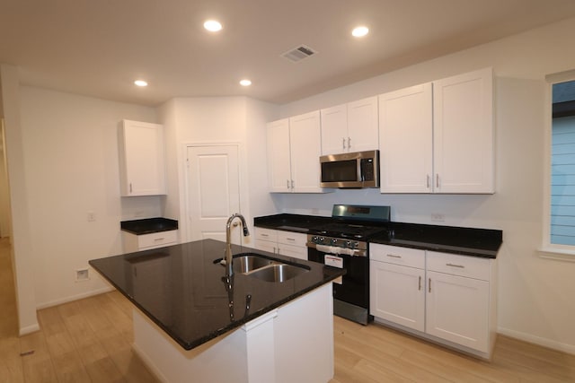 kitchen featuring appliances with stainless steel finishes, a kitchen island with sink, sink, white cabinets, and light hardwood / wood-style floors