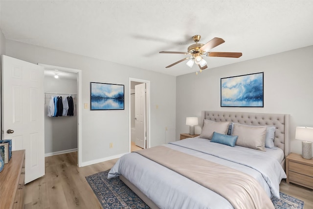 bedroom with ensuite bathroom, ceiling fan, a spacious closet, light hardwood / wood-style floors, and a closet