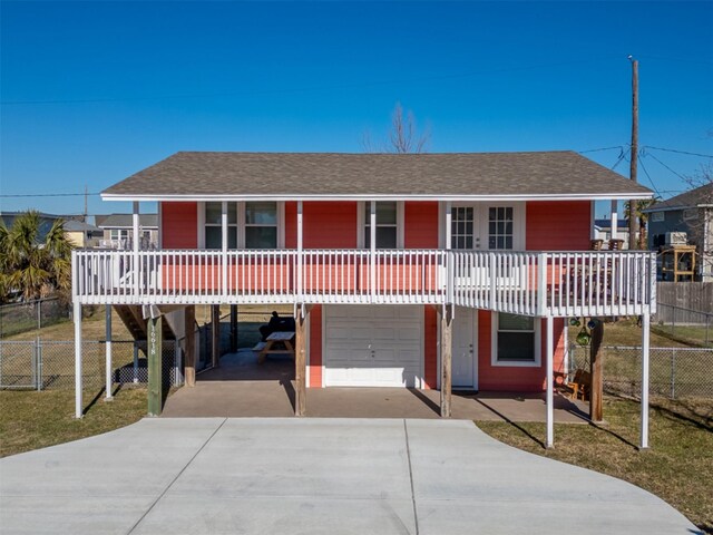 view of front of property featuring concrete driveway, fence, a garage, and roof with shingles