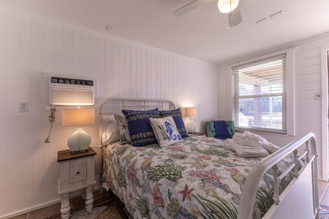 bedroom with tile patterned flooring, ceiling fan, and wooden walls