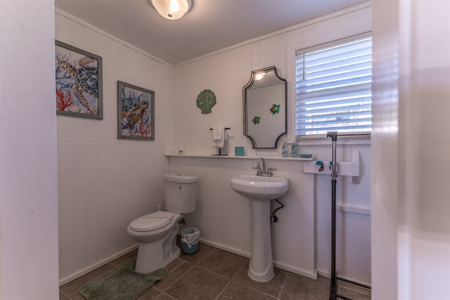 bathroom featuring tile patterned flooring, crown molding, and toilet