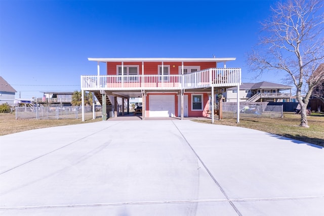 beach home featuring fence, stairway, covered porch, concrete driveway, and a garage