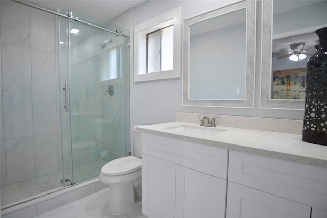 bathroom featuring vanity, a shower with door, tile patterned floors, ceiling fan, and toilet