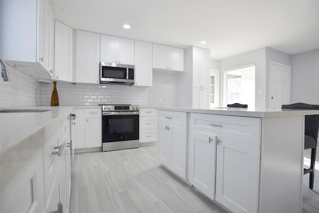 kitchen with white cabinets, appliances with stainless steel finishes, a breakfast bar area, and sink