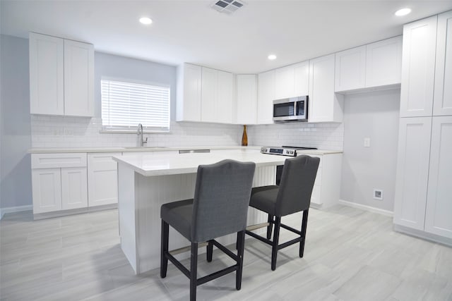 kitchen with a kitchen island, sink, white cabinetry, and stainless steel appliances