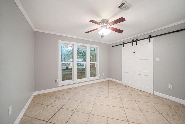 unfurnished room featuring a barn door, ceiling fan, ornamental molding, and light tile patterned flooring