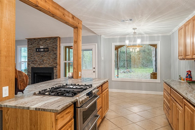 kitchen featuring high end range, light stone countertops, crown molding, a stone fireplace, and hanging light fixtures