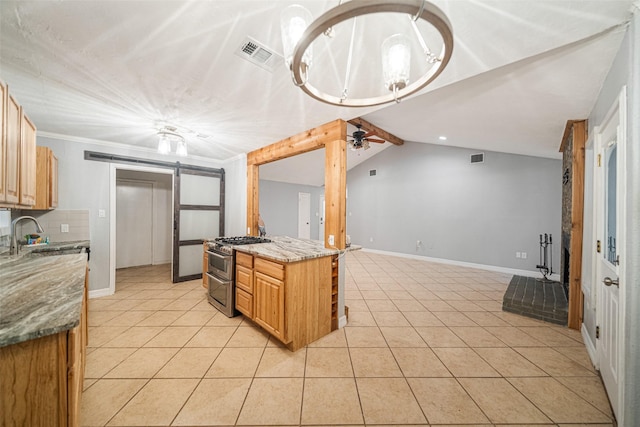 kitchen with light stone countertops, high end stainless steel range oven, ceiling fan, sink, and a barn door