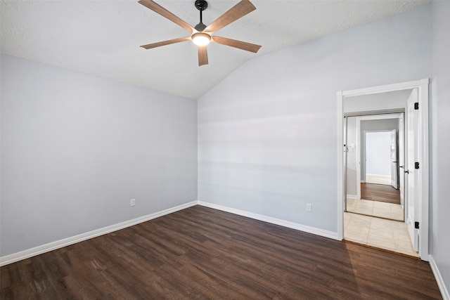 spare room with a textured ceiling, lofted ceiling, ceiling fan, and dark hardwood / wood-style floors