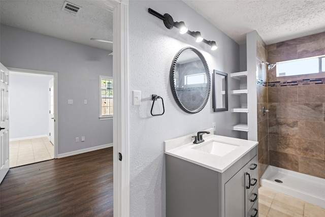 bathroom featuring hardwood / wood-style flooring, tiled shower, a textured ceiling, and vanity