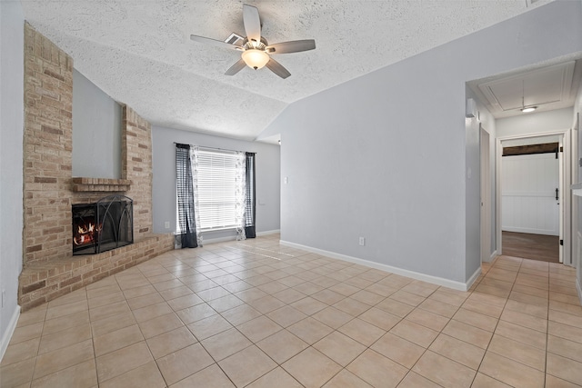 unfurnished living room with lofted ceiling, a brick fireplace, ceiling fan, a textured ceiling, and light tile patterned flooring