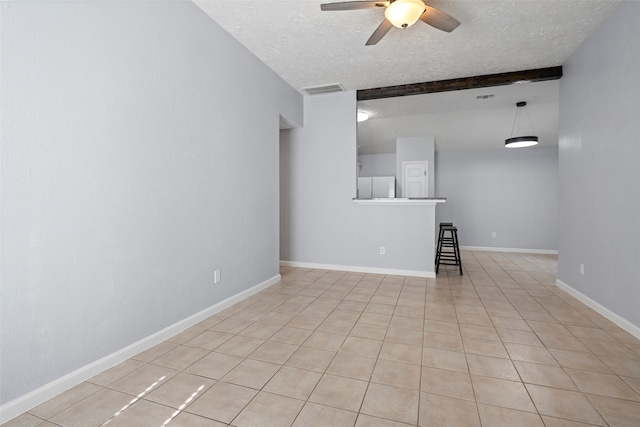 spare room featuring beamed ceiling, light tile patterned floors, a textured ceiling, and ceiling fan