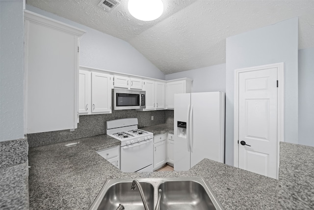 kitchen featuring lofted ceiling, white appliances, white cabinets, sink, and a textured ceiling