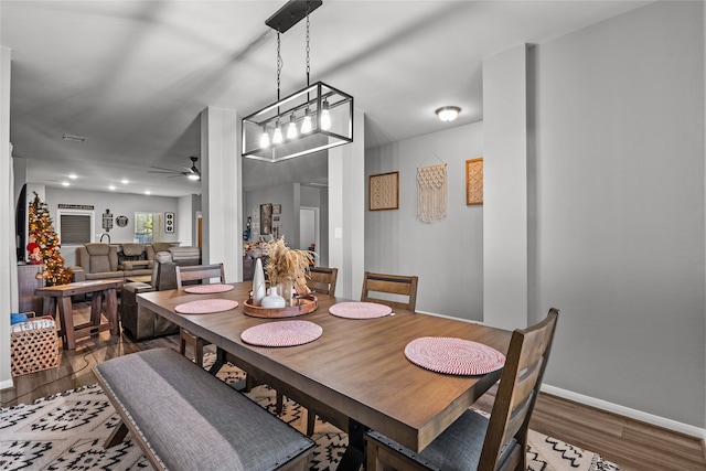 dining room featuring ceiling fan with notable chandelier and hardwood / wood-style flooring