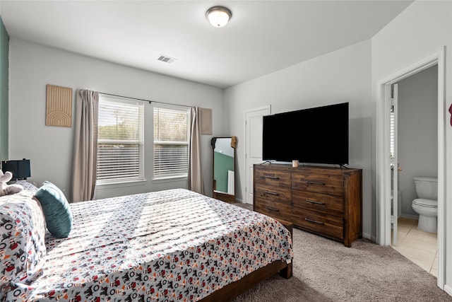 bedroom featuring light carpet and connected bathroom