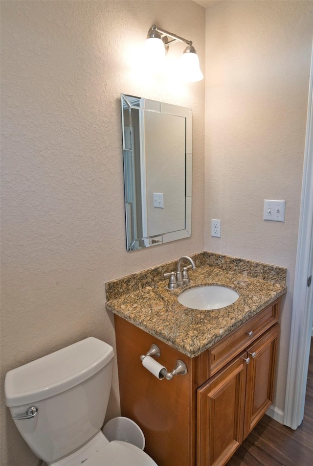 bathroom with hardwood / wood-style floors, vanity, and toilet