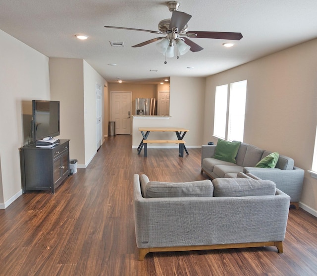 living room featuring dark hardwood / wood-style floors, ceiling fan, and a textured ceiling