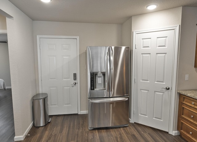 kitchen featuring stainless steel fridge, dark hardwood / wood-style flooring, a textured ceiling, and light stone counters