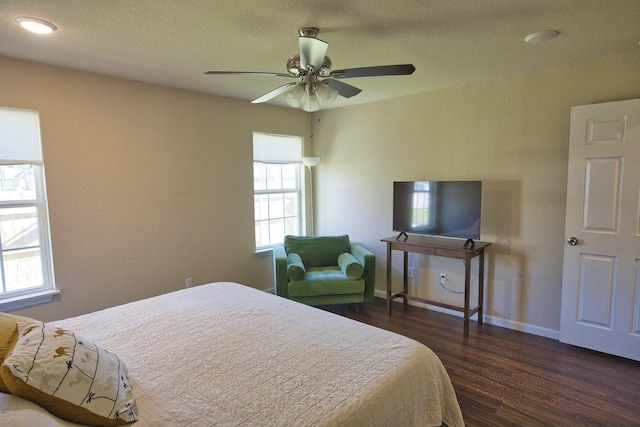 bedroom with multiple windows, a textured ceiling, dark hardwood / wood-style floors, and ceiling fan