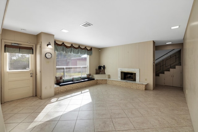 unfurnished living room featuring light tile patterned flooring and a brick fireplace