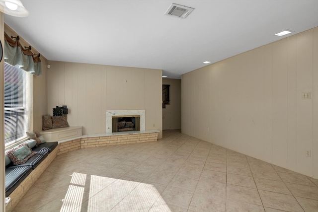 unfurnished living room with a fireplace, wood walls, and light tile patterned flooring