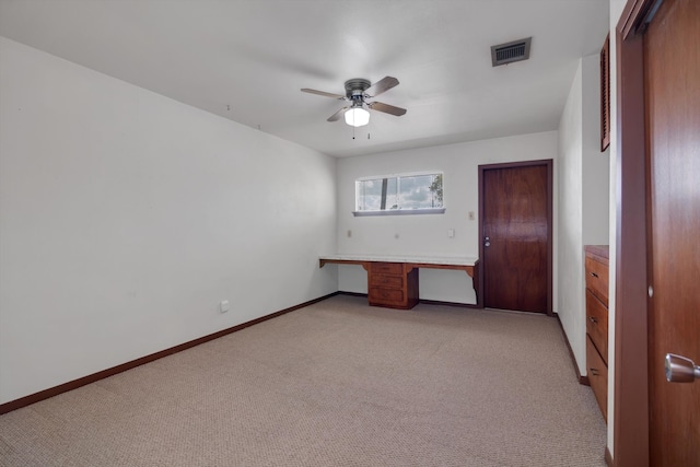 unfurnished bedroom with ceiling fan, light colored carpet, and built in desk