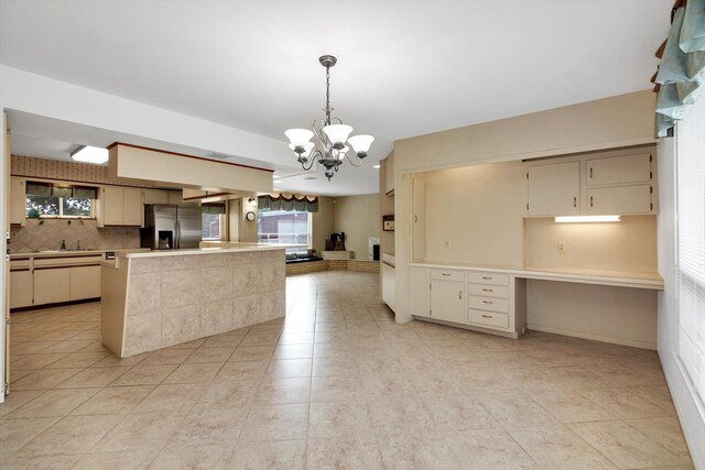 kitchen with stainless steel fridge with ice dispenser, a notable chandelier, cream cabinets, decorative light fixtures, and decorative backsplash