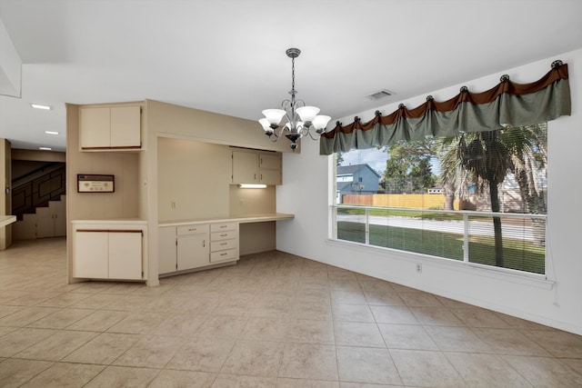 kitchen featuring cream cabinets, built in desk, light tile patterned floors, and pendant lighting