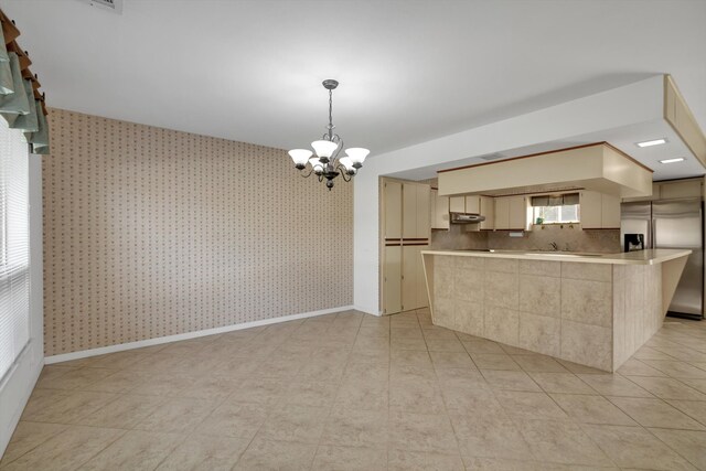 kitchen with kitchen peninsula, stainless steel fridge with ice dispenser, decorative light fixtures, and a notable chandelier