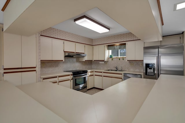 kitchen with white cabinetry, sink, stainless steel appliances, tasteful backsplash, and kitchen peninsula