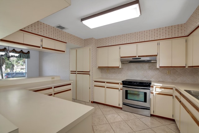 kitchen featuring decorative backsplash, light tile patterned flooring, stainless steel electric range, and cream cabinetry