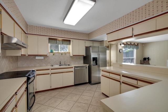 kitchen featuring decorative backsplash, appliances with stainless steel finishes, sink, light tile patterned floors, and cream cabinets