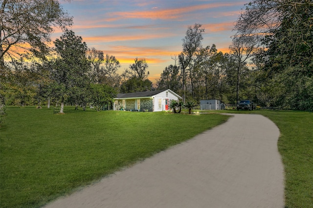 view of property's community with a lawn and a storage shed