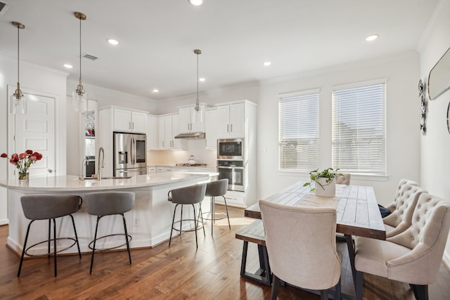 kitchen featuring white cabinets, appliances with stainless steel finishes, dark wood-type flooring, and pendant lighting