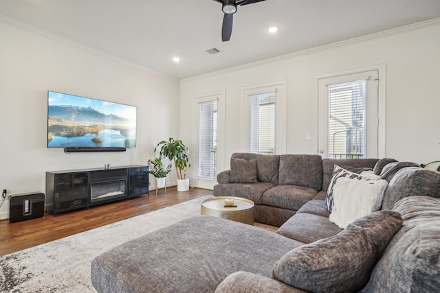 living room with crown molding, ceiling fan, and dark wood-type flooring